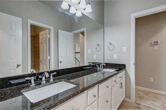 full bath with double vanity, tile patterned floors, baseboards, and a sink