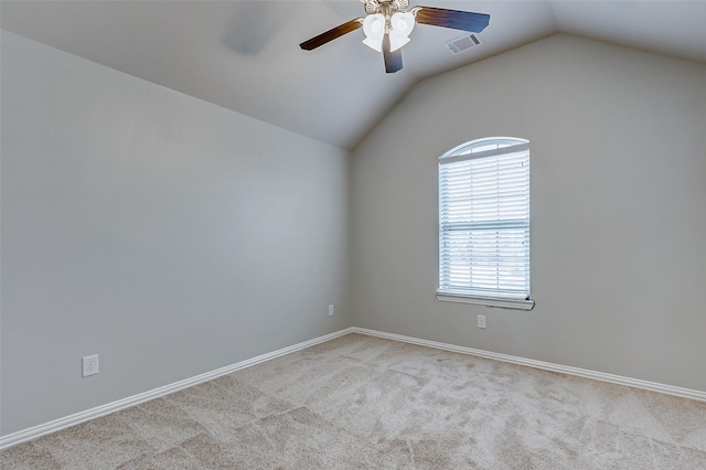 carpeted spare room with vaulted ceiling, a ceiling fan, and visible vents