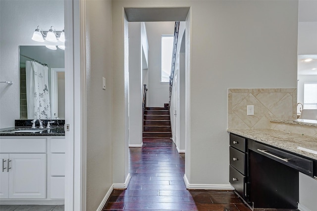 interior space featuring light stone counters, dark wood-style flooring, a sink, decorative backsplash, and white cabinetry