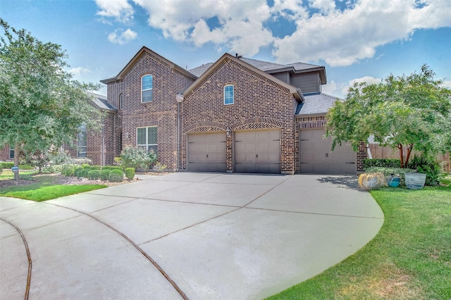 traditional-style home featuring a front lawn, concrete driveway, an attached garage, a shingled roof, and brick siding