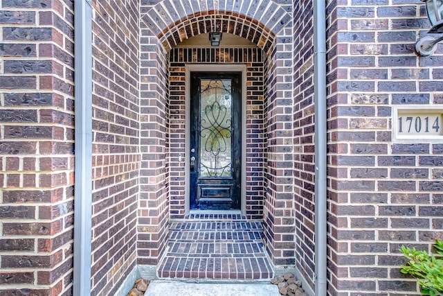 doorway to property featuring brick siding