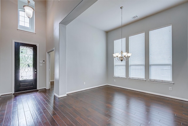 foyer entrance with baseboards, visible vents, a high ceiling, dark wood-style flooring, and a chandelier