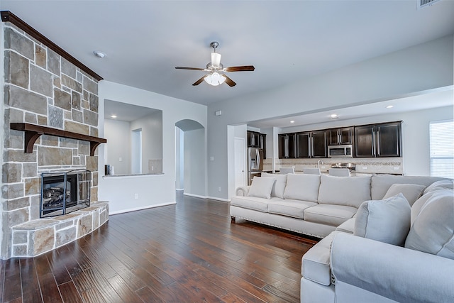 unfurnished living room featuring a fireplace, dark wood-type flooring, and ceiling fan