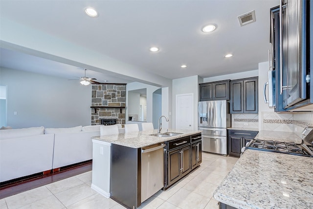 kitchen with tasteful backsplash, visible vents, a sink, appliances with stainless steel finishes, and a kitchen island with sink