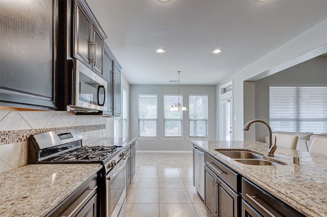 kitchen featuring pendant lighting, light tile patterned floors, stainless steel appliances, sink, and decorative backsplash