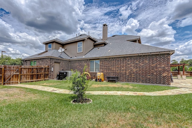 rear view of property with fence, roof with shingles, a yard, a chimney, and brick siding