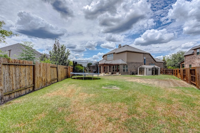 view of yard featuring a fenced backyard, a trampoline, a storage shed, and an outdoor structure