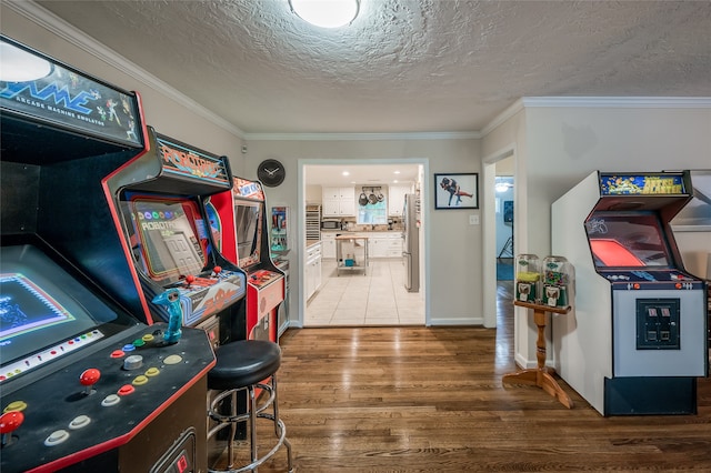 game room featuring a textured ceiling, ornamental molding, and hardwood / wood-style floors