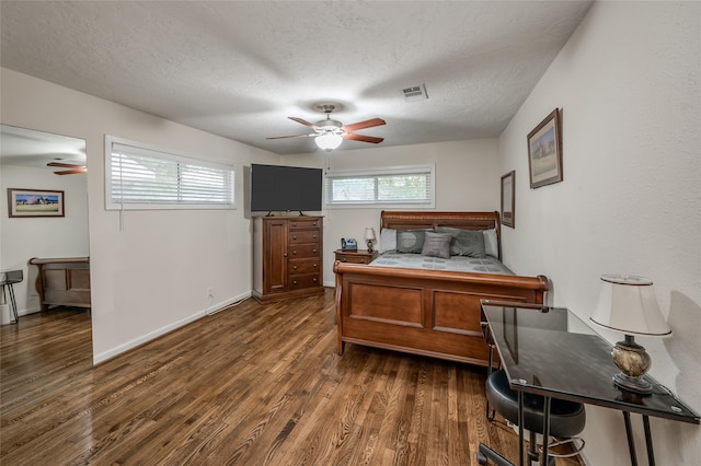 bedroom with a textured ceiling, ceiling fan, and dark hardwood / wood-style floors