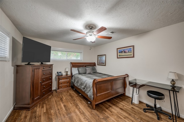 bedroom with a textured ceiling, dark wood-type flooring, and ceiling fan