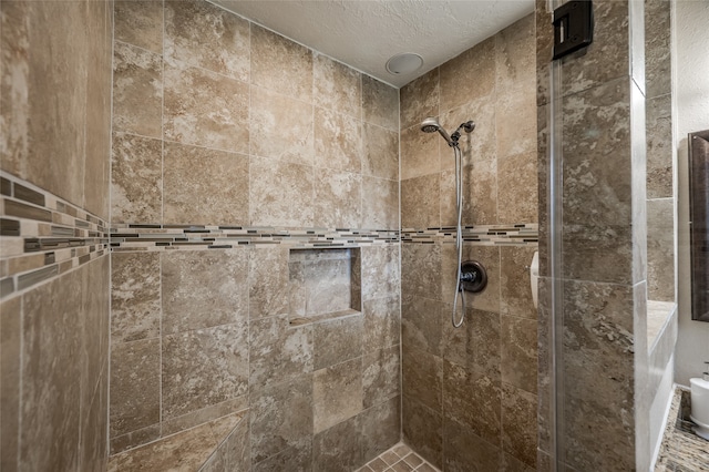 bathroom with a textured ceiling and a tile shower