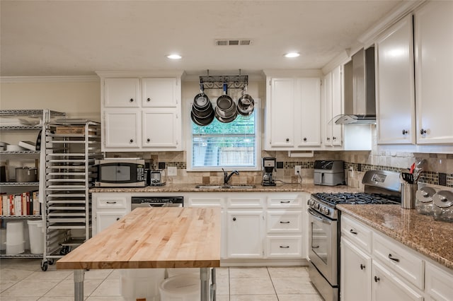 kitchen with appliances with stainless steel finishes, sink, white cabinetry, and wood counters