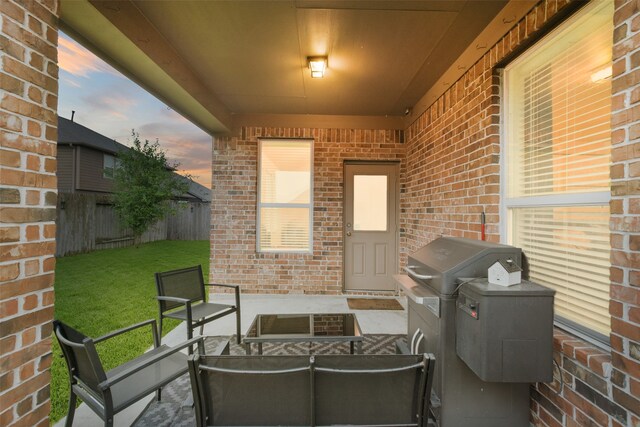 patio terrace at dusk with area for grilling and a lawn