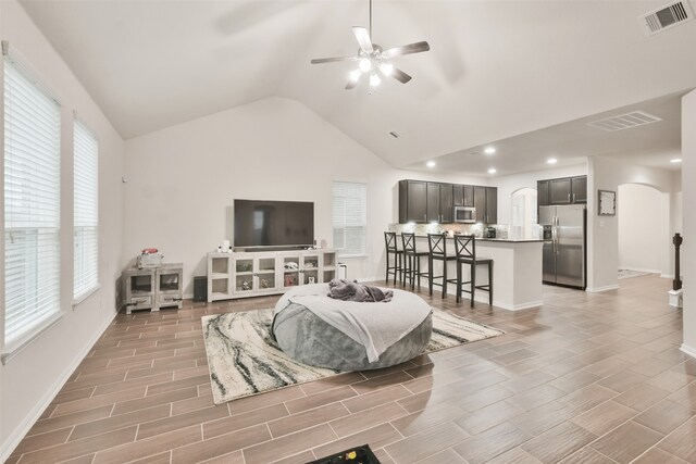 living room with high vaulted ceiling, ceiling fan, and light wood-type flooring