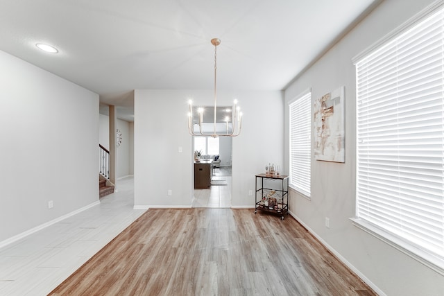 unfurnished dining area featuring light hardwood / wood-style flooring and an inviting chandelier