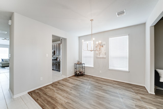 unfurnished dining area featuring light hardwood / wood-style flooring and a chandelier