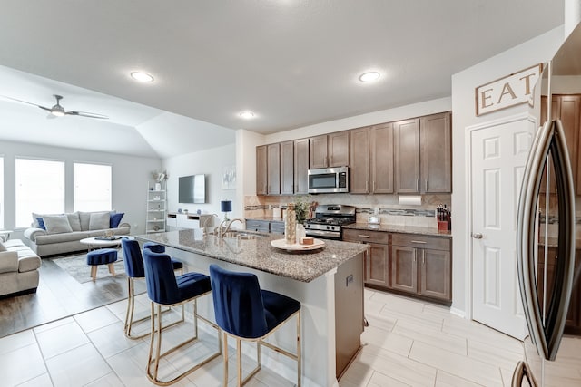 kitchen featuring stainless steel appliances, sink, a breakfast bar area, an island with sink, and ceiling fan