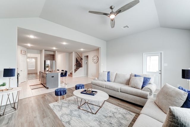 living room with lofted ceiling, ceiling fan, and light wood-type flooring