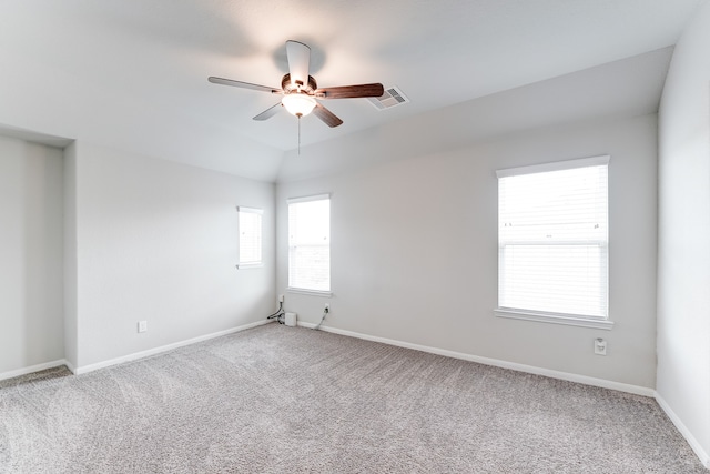 carpeted spare room with ceiling fan, plenty of natural light, and vaulted ceiling