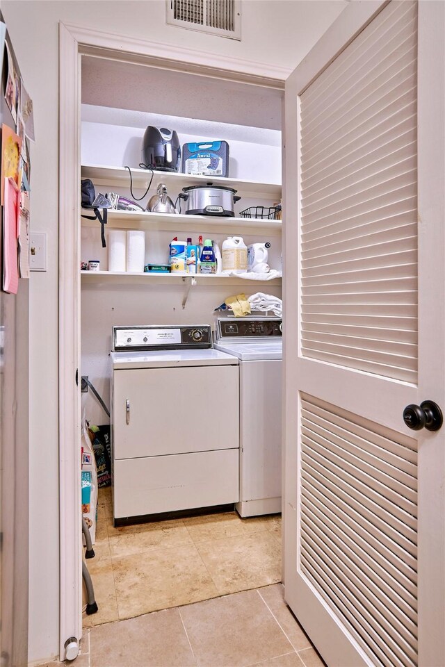 laundry room featuring washing machine and dryer and light tile patterned floors