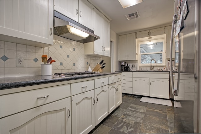 kitchen featuring stainless steel refrigerator, sink, decorative backsplash, and white cabinets