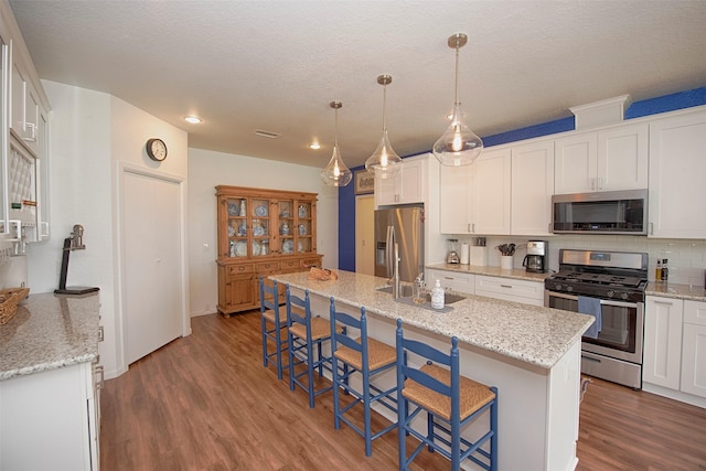 3821 Nasa Rd Unit 1, Seabrook, TX 77586 - kitchen with appliances with stainless steel finishes, dark wood-style flooring, white cabinetry, a kitchen breakfast bar, and a kitchen island with sink