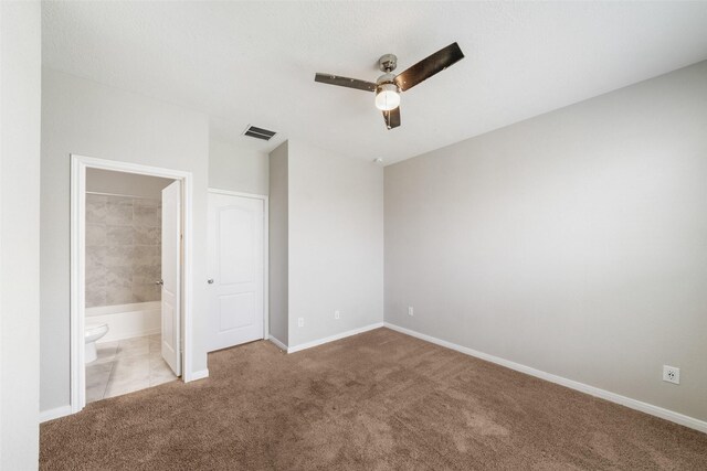 unfurnished bedroom featuring light colored carpet, ensuite bathroom, and ceiling fan