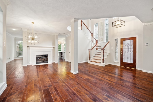 entryway with crown molding, a notable chandelier, a fireplace, and dark hardwood / wood-style flooring