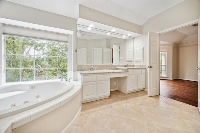 bathroom with vanity, hardwood / wood-style floors, a bathtub, and lofted ceiling