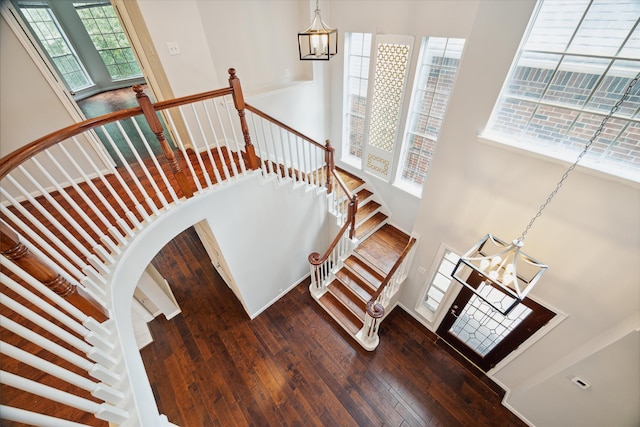 staircase with hardwood / wood-style flooring and a chandelier