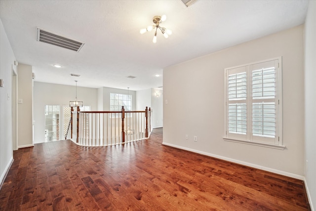 spare room featuring a notable chandelier and dark hardwood / wood-style flooring