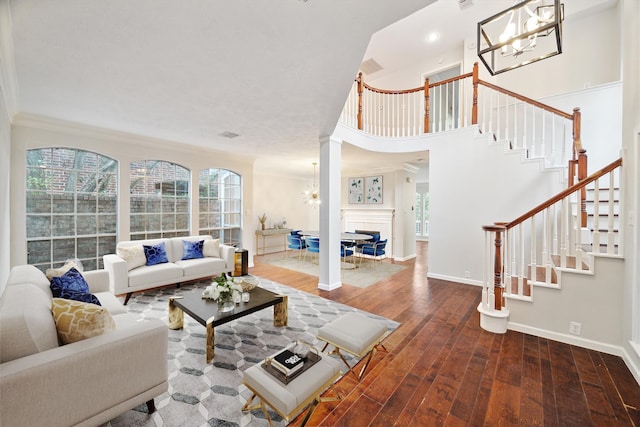 living room featuring decorative columns, crown molding, wood-type flooring, and a chandelier