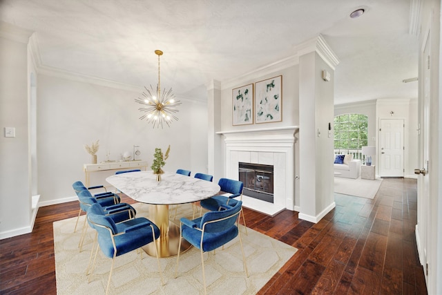 dining space with ornamental molding, an inviting chandelier, dark hardwood / wood-style floors, and a fireplace