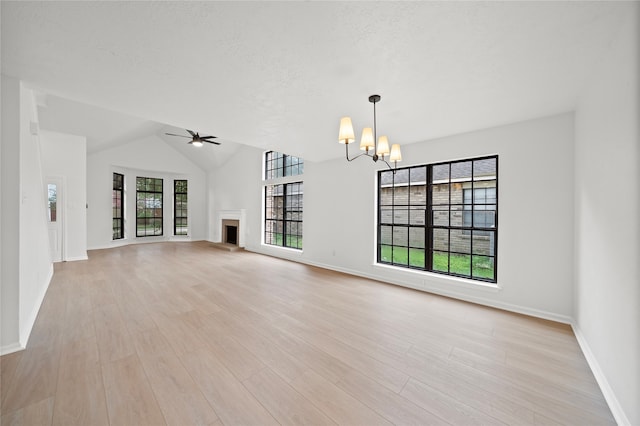 unfurnished living room featuring ceiling fan with notable chandelier, light wood-type flooring, and lofted ceiling