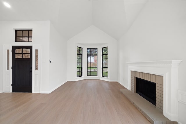 unfurnished living room featuring light hardwood / wood-style flooring and a brick fireplace