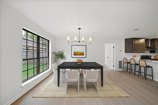 dining area with light hardwood / wood-style flooring and a chandelier