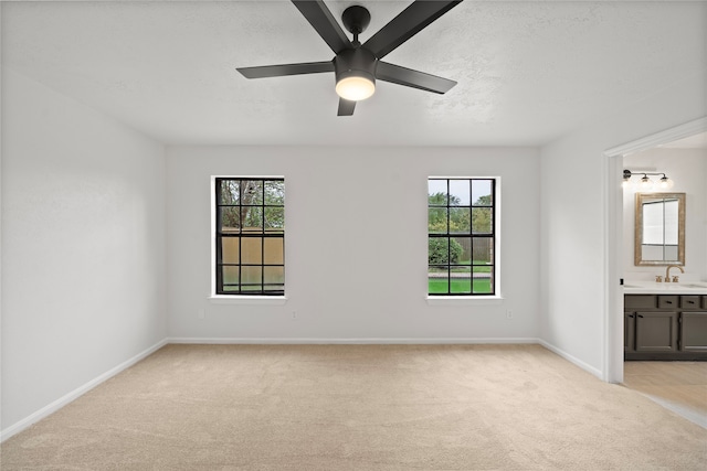 carpeted empty room with a wealth of natural light, sink, and ceiling fan