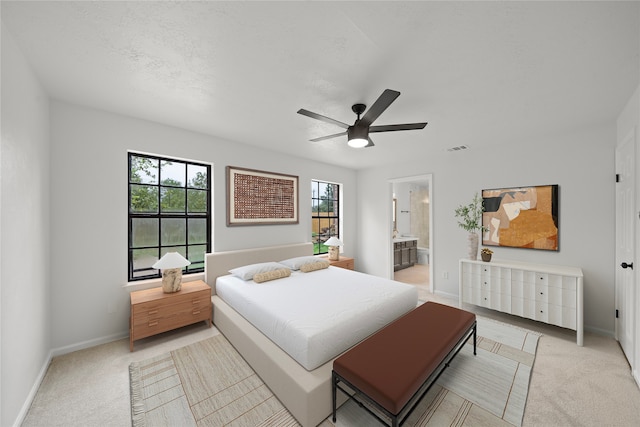 carpeted bedroom featuring multiple windows, connected bathroom, and ceiling fan