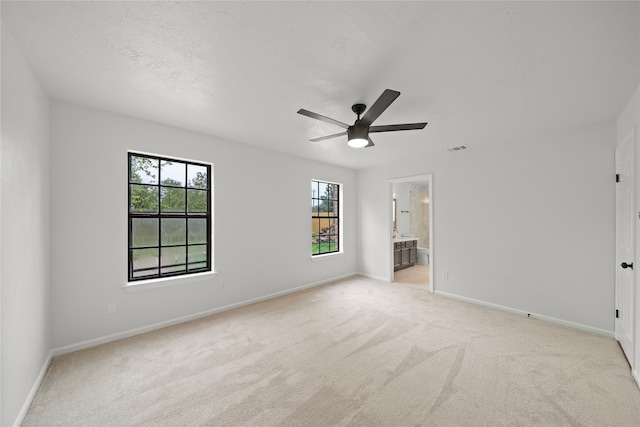 carpeted spare room featuring a wealth of natural light and ceiling fan