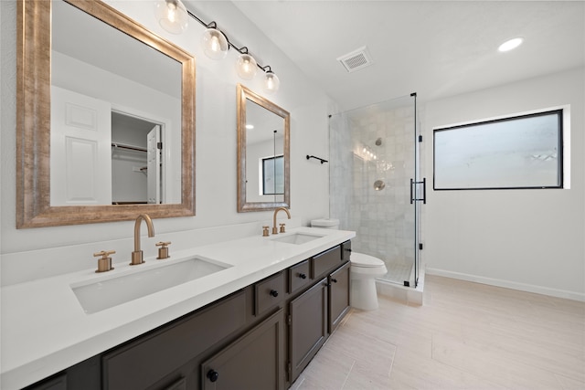 bathroom featuring vanity, toilet, and a shower with shower door