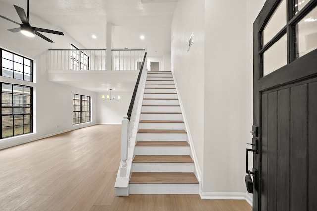 interior space with hardwood / wood-style floors, ceiling fan with notable chandelier, and high vaulted ceiling