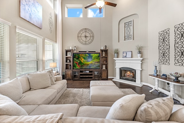 living room with a towering ceiling, dark hardwood / wood-style floors, and ceiling fan