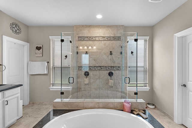 bathroom featuring a healthy amount of sunlight, independent shower and bath, tile patterned flooring, and vanity