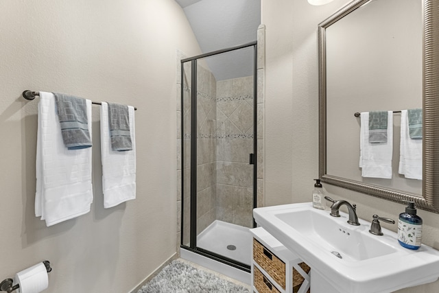 bathroom with vaulted ceiling, a shower with shower door, and sink