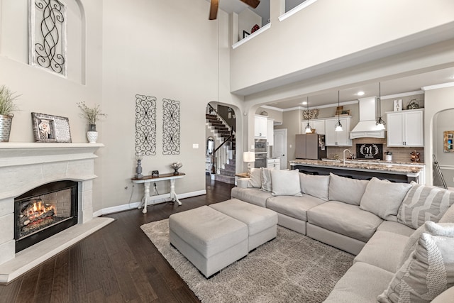 living room with crown molding, a towering ceiling, dark hardwood / wood-style flooring, and sink