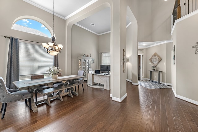 dining space featuring ornamental molding, a towering ceiling, a chandelier, and dark hardwood / wood-style flooring