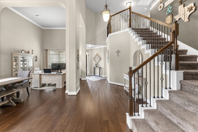 entryway with crown molding, a towering ceiling, and dark hardwood / wood-style flooring