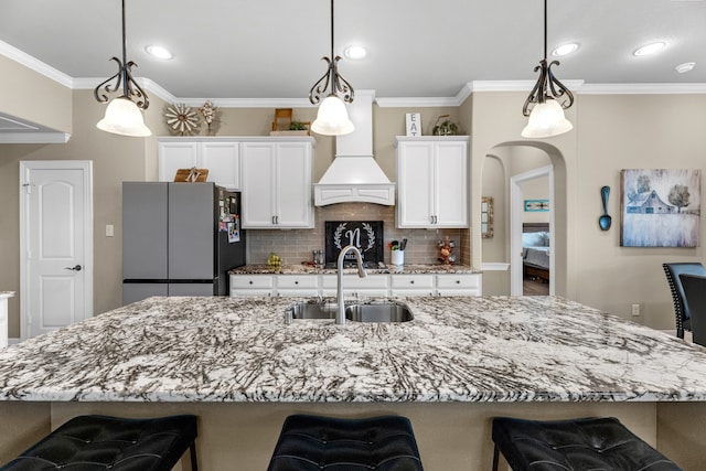 kitchen with a kitchen breakfast bar, stainless steel refrigerator, sink, and decorative light fixtures