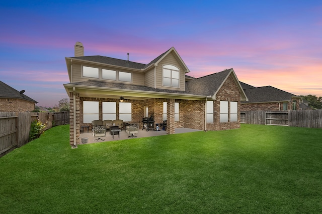 back house at dusk with a patio and a yard