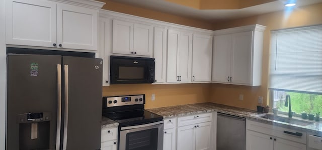 kitchen with stone countertops, appliances with stainless steel finishes, white cabinetry, and sink